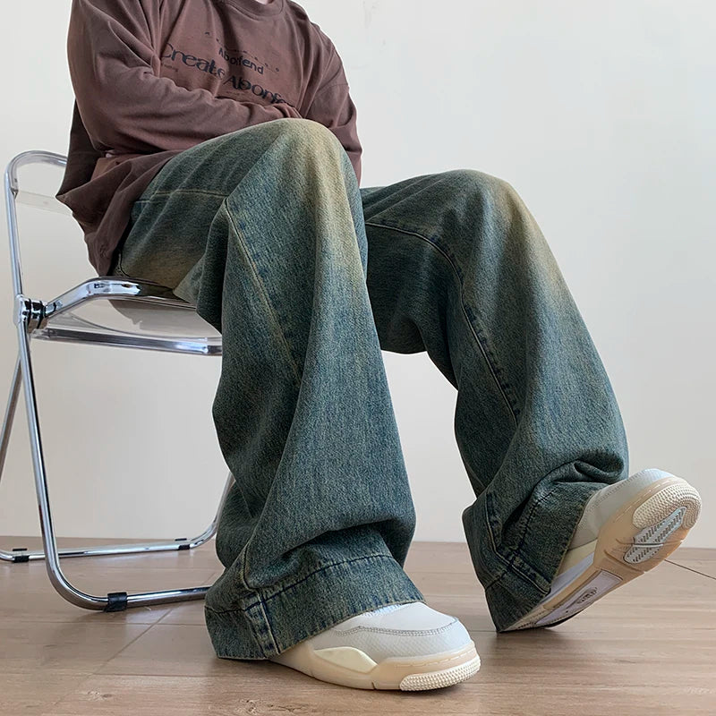 Person wearing distressed wide leg jeans sitting on a metal chair with white sneakers on wooden floor