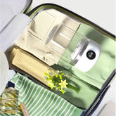1L compact laundry cleaner by AngShop placed in packed suitcase with folded clothes and flowers