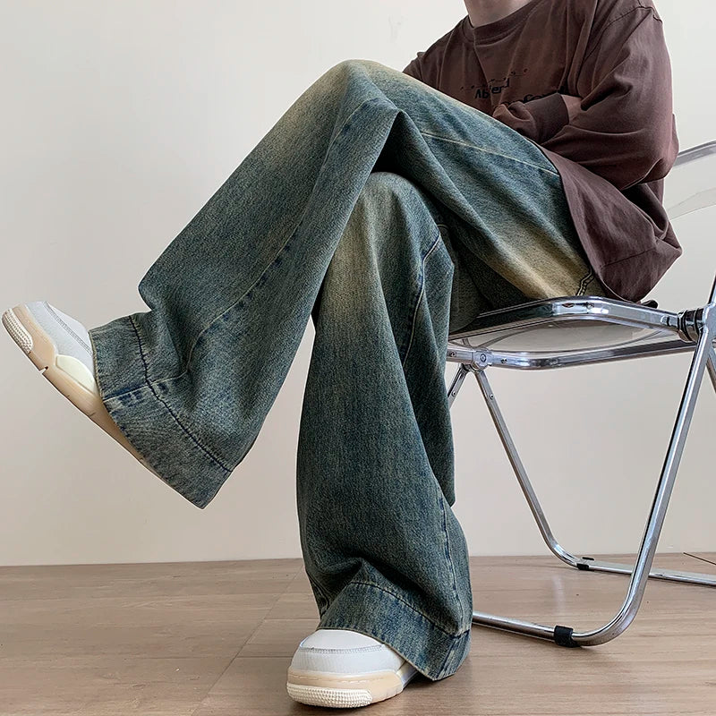AngShop distressed wide leg jeans with faded wash worn with white sneakers seated on a metal chair