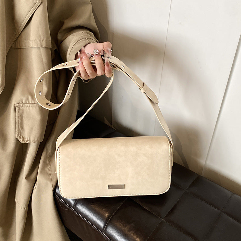 Beige functional elegant purse women holding by strap with stylish trench coat background