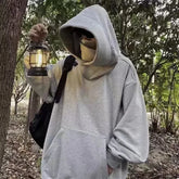 Person wearing grey Harajuku fashion hoodie unisex holding a lantern in an outdoor wooded area