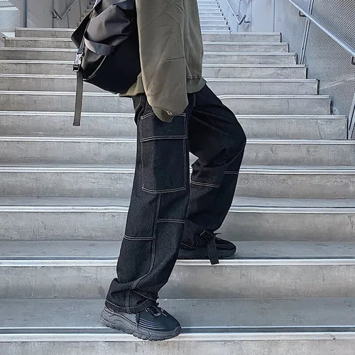 Black casual cargo trousers for men with multiple pockets worn with black sneakers and green jacket