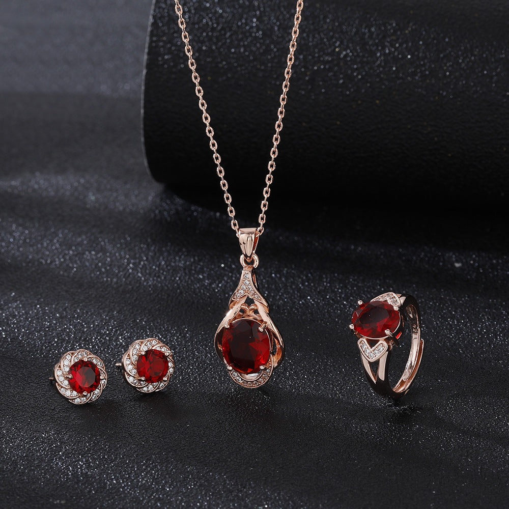 Elegant red tourmaline necklace and earrings set with gold and diamond accents on black background