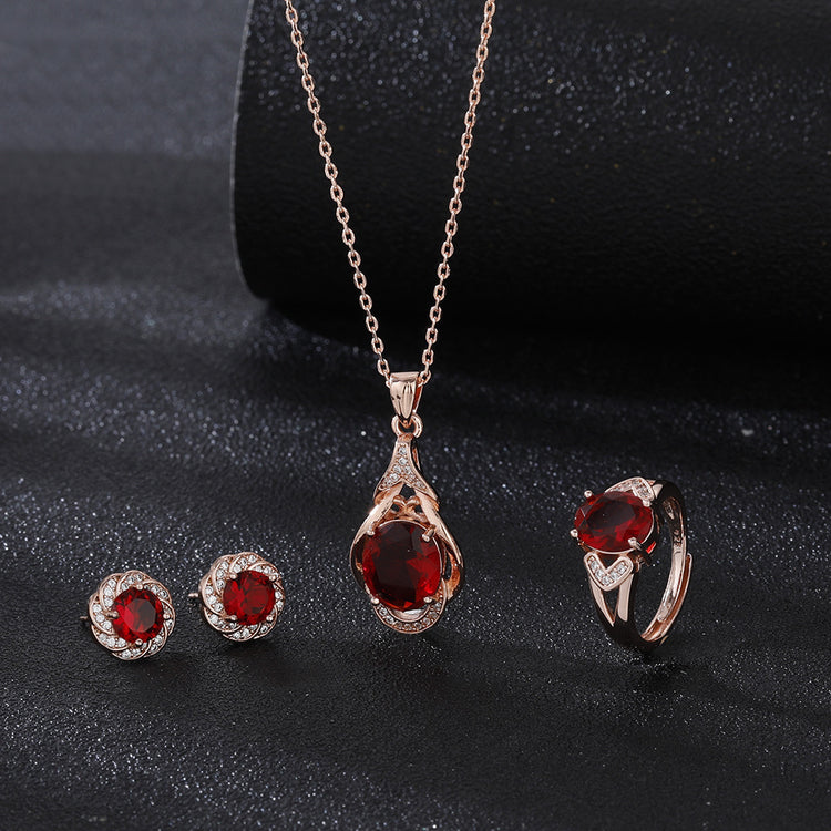 Elegant red tourmaline necklace and earrings set with gold and diamond accents on black background
