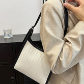 Elegant stitched handbag for women in cream and black worn over beige blazer sleeve