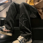 Black gothic streetwear pants with distressed star patches paired with patterned sneakers