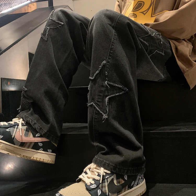 Black gothic streetwear pants with distressed star patches paired with patterned sneakers