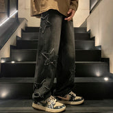 AngShop black gothic streetwear pants with star patches worn with black and beige sneakers on stairs